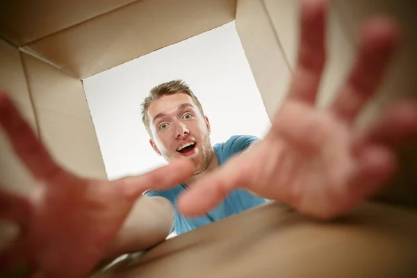 Gülümseyen, açma ve karton kutusunu açıp içeri arayan adam — Stok fotoğraf