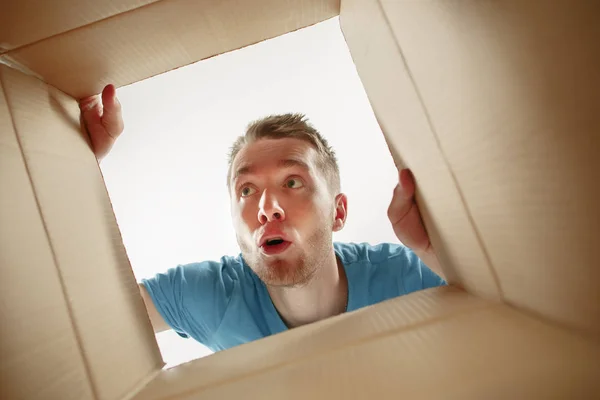 Hombre sonriendo, desempacando y abriendo la caja de cartón y mirando dentro — Foto de Stock