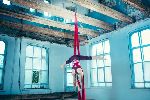 Graceful gymnast performing aerial exercise at loft