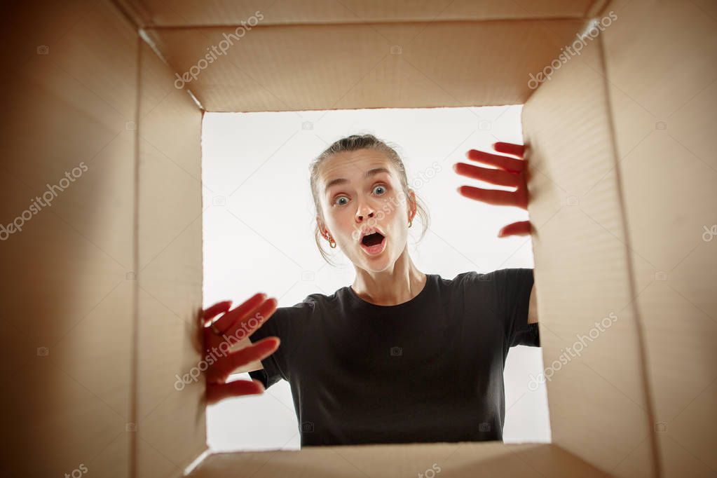 Woman unpacking and opening carton box and looking inside