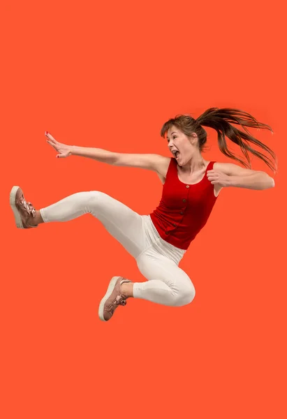 Libertad de movimiento. Mujer bastante joven saltando sobre fondo naranja — Foto de Stock