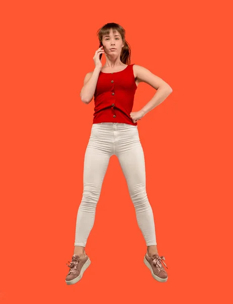 Полная длина симпатичной молодой женщины с мобильным телефоном во время прыжка — стоковое фото