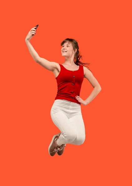 Повна довжина красивої молодої жінки з мобільним телефоном під час стрибків — стокове фото