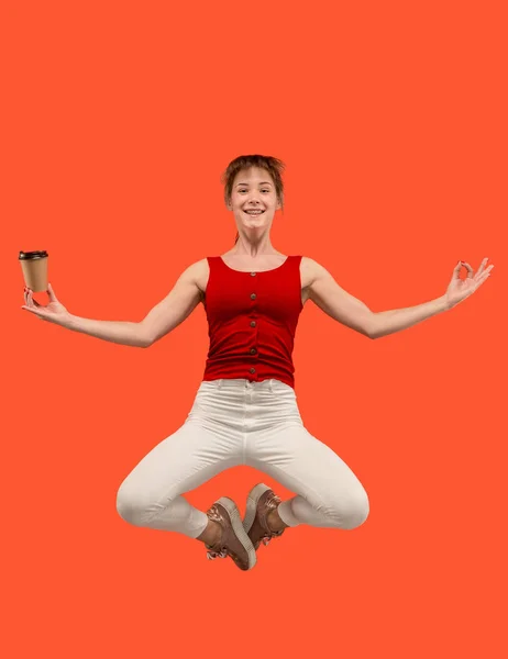 Libertad de movimiento. Mujer bastante joven saltando sobre fondo naranja — Foto de Stock