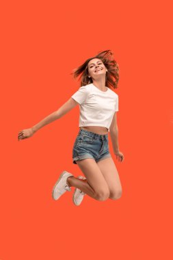 Hareketli bir özgürlük. Havada atlama ve turuncu studio arka planı el hareketi oldukça mutlu genç kadın bir kadeh. Hareket veya taşıma koşturma kız. İnsan duygu ve yüz ifadeleri kavramı