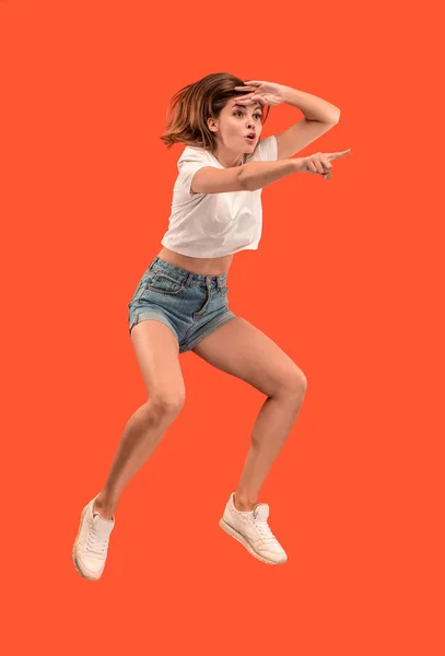 Liberdade em movimento. Mulher muito jovem pulando contra fundo laranja — Fotografia de Stock