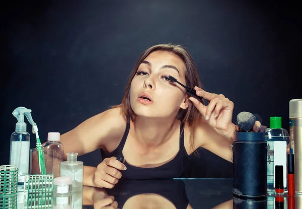 Mulher de beleza aplicando maquiagem. Menina bonita olhando no espelho e aplicando cosméticos com uma escova grande . — Fotografia de Stock