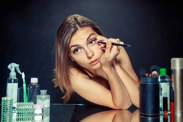 Mujer de belleza aplicando maquillaje. Hermosa chica mirando en el espejo y la aplicación de cosméticos con un cepillo grande . — Foto de Stock