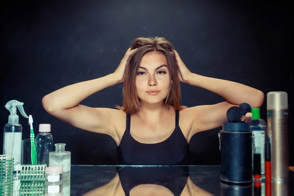 Mulher de beleza depois de aplicar maquiagem. Menina bonita olhando no espelho e aplicando cosméticos com uma escova . — Fotografia de Stock