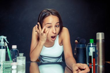 Güzellik kadını makyaj uygulamak. Aynaya bakıyorum ve kozmetik bir göz kalemi ile uygulama güzel kız.