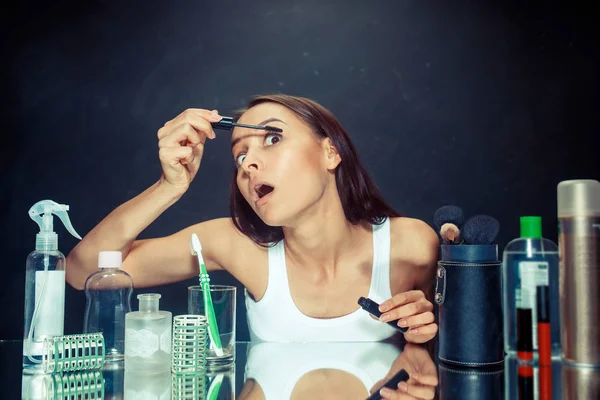 Mujer de belleza aplicando maquillaje. Hermosa chica mirando en el espejo y la aplicación de cosméticos con un cepillo . — Foto de Stock