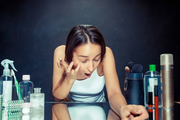 Mulher de beleza aplicando maquiagem. Menina bonita olhando no espelho e aplicando cosméticos com um lápis de olho . — Fotografia de Stock