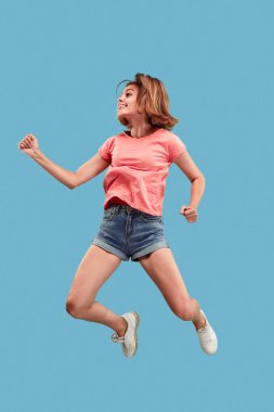 Hareketli bir özgürlük. Genç ve güzel kadın karşı mavi arka plan atlama