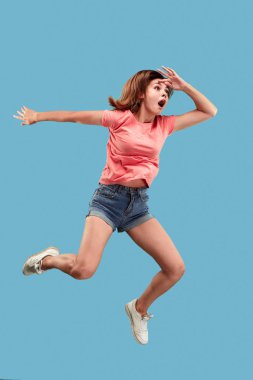 Hareketli bir özgürlük. Genç ve güzel kadın karşı mavi arka plan atlama