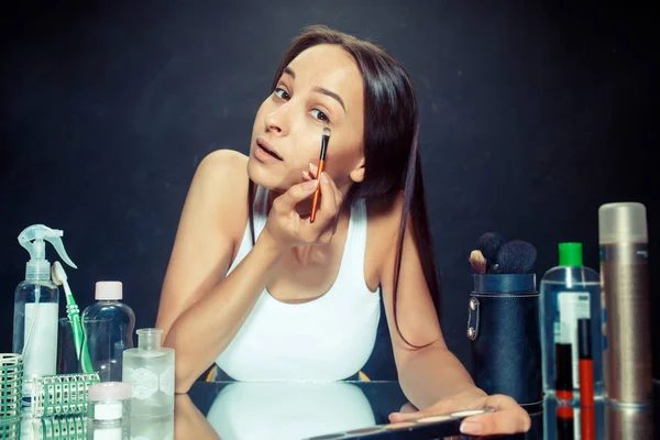 Güzellik kadını makyaj uygulamak. Aynaya bakıyorum ve bir fırça ile kozmetik uygulama güzel kız. — Stok fotoğraf