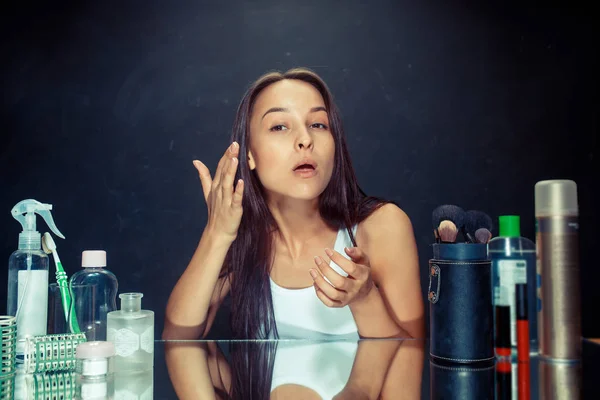 Mujer de belleza después de aplicar maquillaje. Hermosa chica mirando en el espejo y la aplicación de cosméticos con un cepillo . — Foto de Stock