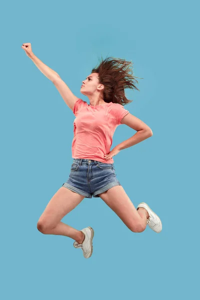 Свобода передвижения. Красивая молодая женщина прыгает на синем фоне — стоковое фото