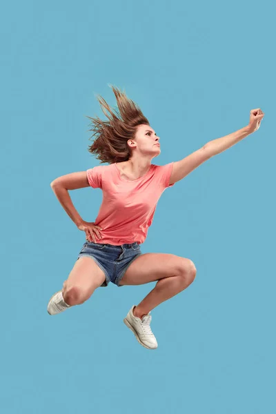 Frihet i rörelse. Ganska ung kvinna hoppa mot blå bakgrund — Stockfoto