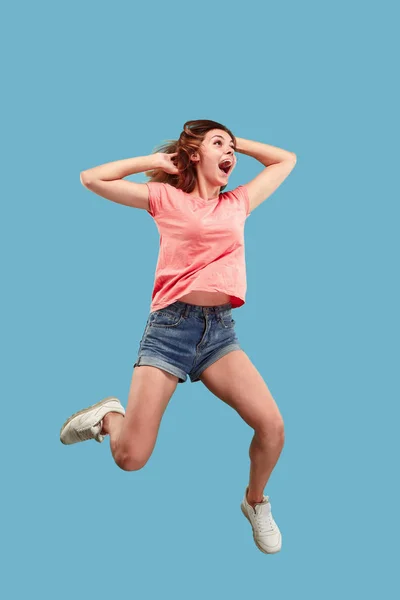 Libertad de movimiento. Mujer bastante joven saltando sobre fondo azul — Foto de Stock