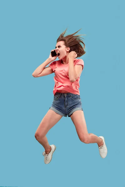 Longitud completa de la mujer joven y bonita con teléfono móvil mientras salta — Foto de Stock
