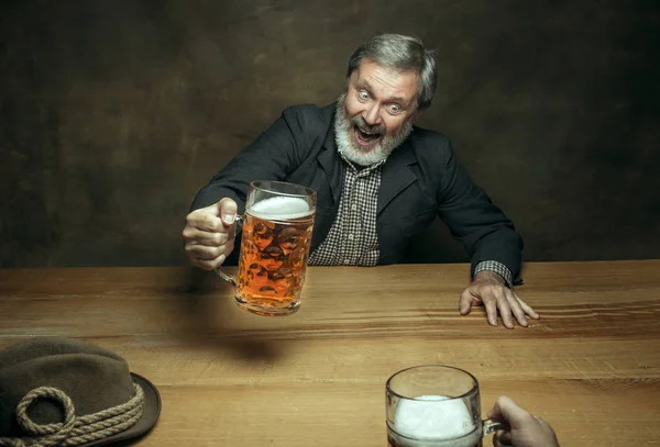 Lächelnder bärtiger Mann trinkt Bier in Kneipe — Stockfoto