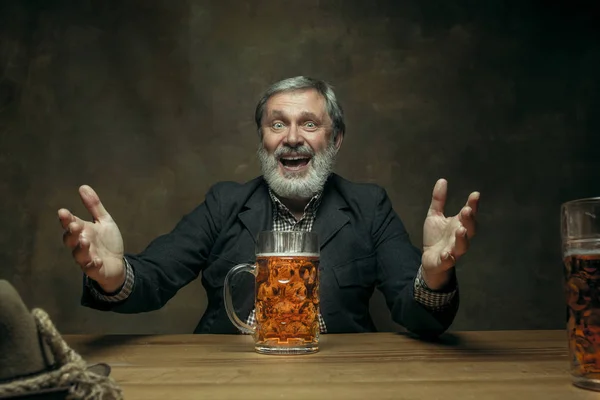 Lächelnder bärtiger Mann trinkt Bier in Kneipe — Stockfoto