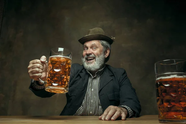 Lächelnder bärtiger Mann trinkt Bier in Kneipe — Stockfoto