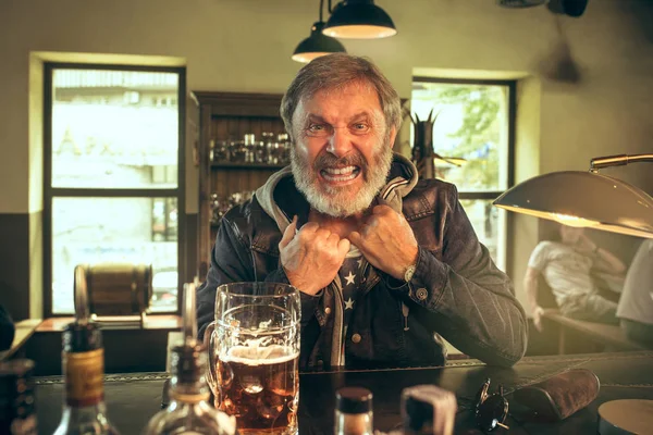 Der ältere bärtige Mann trinkt Bier in der Kneipe — Stockfoto