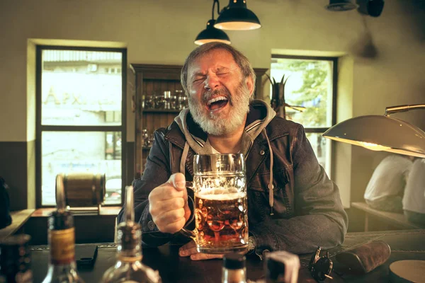 The senior bearded male drinking beer in pub