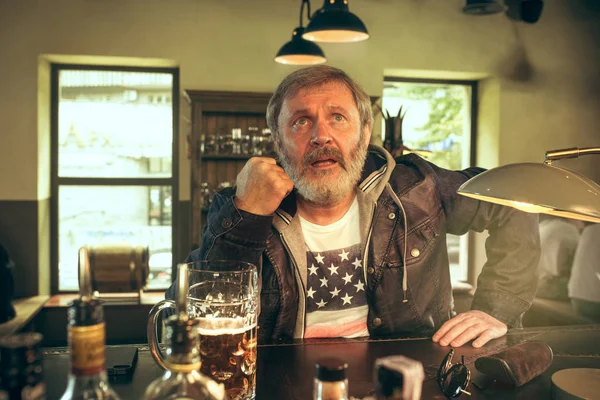 Старший бородатый мужчина пьет пиво в пабе — стоковое фото
