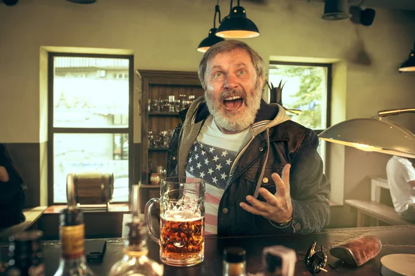 Der ältere bärtige Mann trinkt Bier in der Kneipe — Stockfoto