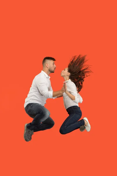 Frihet i rörelse. Ganska ungt par hoppar mot röd bakgrund — Stockfoto