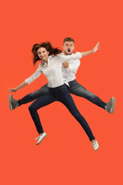 Freedom in moving. Pretty young couple jumping against red background — Stock Photo, Image