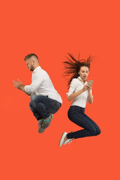 Full length of young couple with mobile phone while jumping — Stock Photo, Image