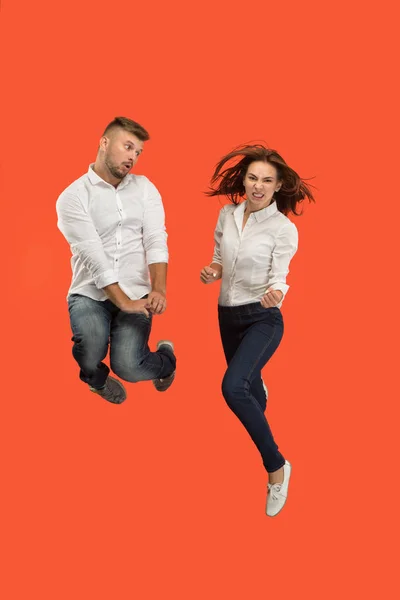 Libertad de movimiento. joven pareja saltando sobre rojo fondo —  Fotos de Stock