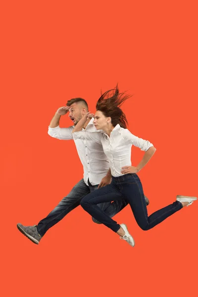 Freedom in moving. Pretty young couple jumping against red background — Stock Photo, Image