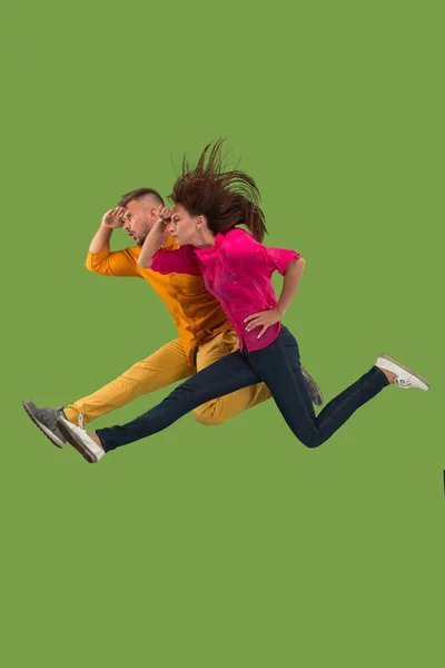 Freedom in moving. Pretty young couple jumping against green background — Stock Photo, Image