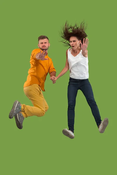 Свобода передвижения. Красивая молодая пара прыгает на зеленом фоне — стоковое фото