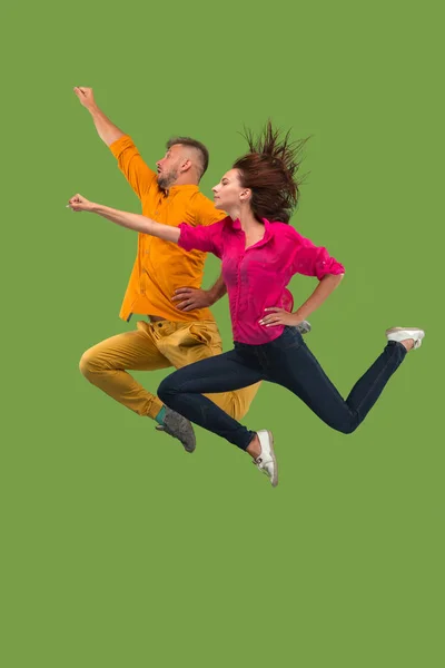 Freiheit in der Bewegung. hübsches junges Paar springt vor grünem Hintergrund — Stockfoto