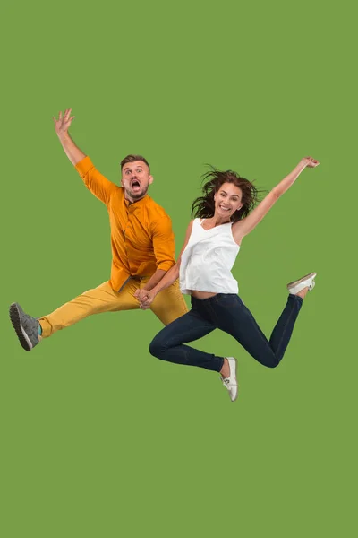 Frihet i rörelse. Ganska ungt par hoppar mot grön bakgrund — Stockfoto