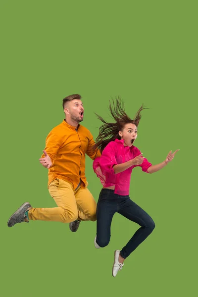 Liberdade em movimento. Casal muito jovem pulando contra fundo verde — Fotografia de Stock