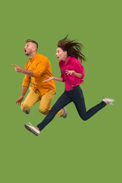 Свобода передвижения. Красивая молодая пара прыгает на зеленом фоне — стоковое фото