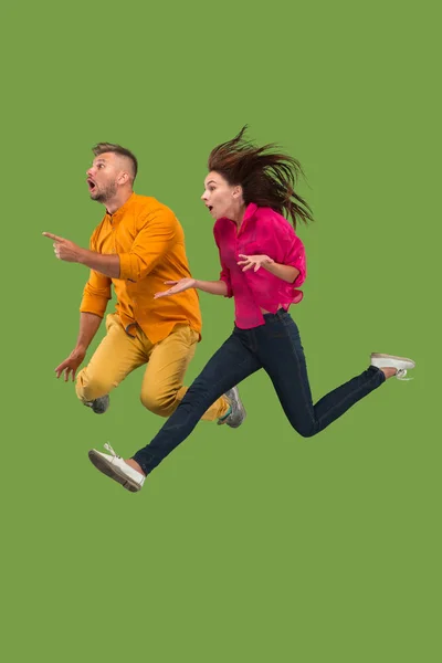 Freedom in moving. Pretty young couple jumping against green background — Stock Photo, Image