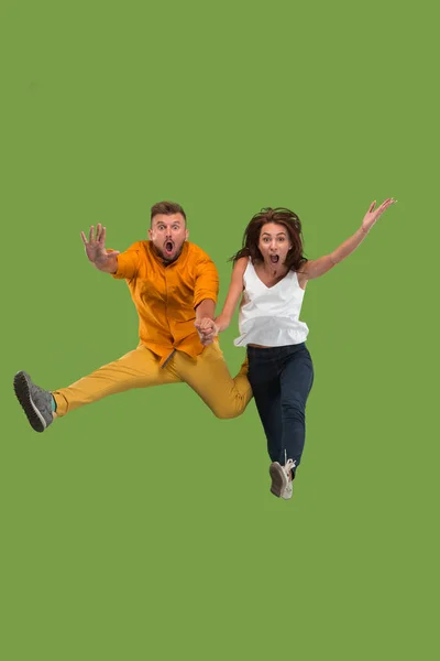 Libertad de movimiento. Bastante joven pareja saltando sobre fondo verde — Foto de Stock