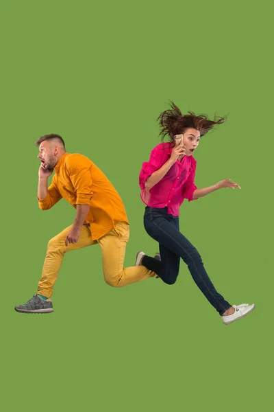 Comprimento total do jovem casal com telefone celular enquanto salta — Fotografia de Stock