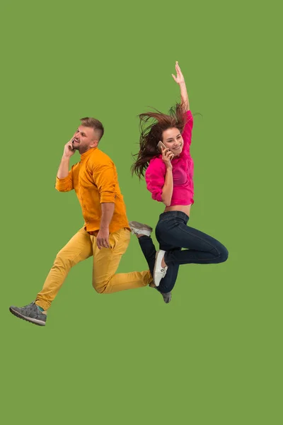 年轻夫妇在跳跃时用手机的全长 — 图库照片