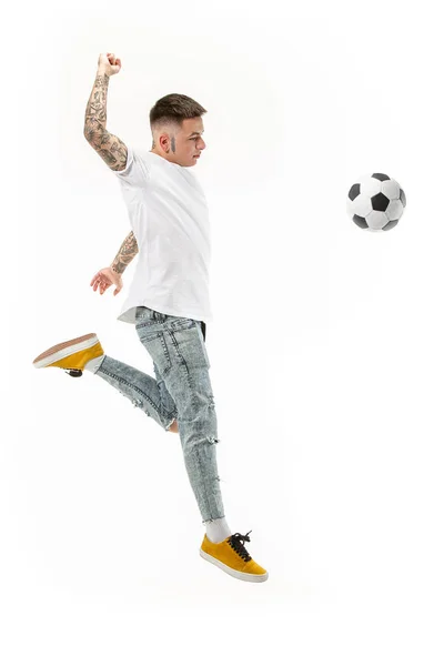 O jovem como jogador de futebol chutando a bola no estúdio — Fotografia de Stock