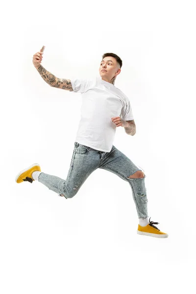Longitud completa de joven guapo tomando selfie mientras salta — Foto de Stock