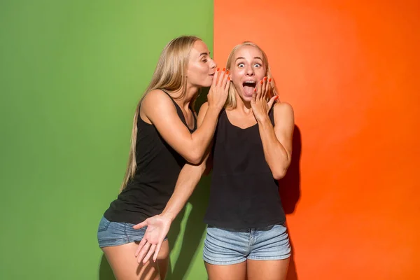 The young woman whispering a secret behind her hand over studio background — Stock Photo, Image