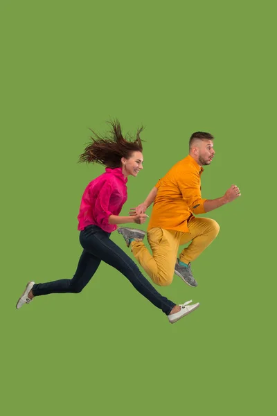 Hareketli bir özgürlük. Oldukça genç bir çift yeşil arka planı atlama — Stok fotoğraf